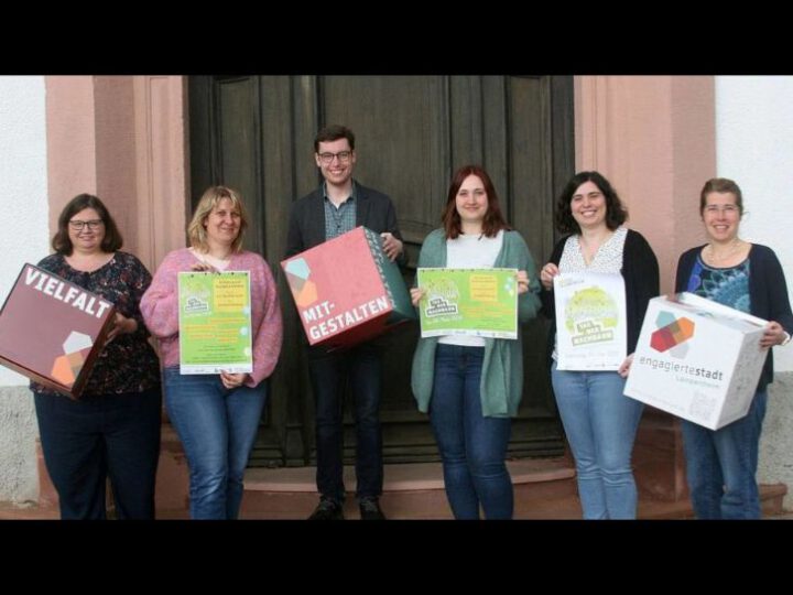 Auf dem Bild stehen sechs Personen mit Plakaten und Würfeln in der Hand. SIe machen Werbung für den Tag der Nachbarn in Lampertheim am 4. Mai 2024