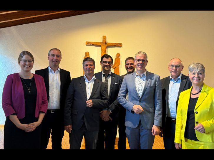 Vor Altar und Kreuz in der evangelischen Stephanus-Gemeinde in Bensheim stehen die Ehrengäste von Diakonie, Kirche und Politik. In der Mitte der ehemalige Leiter der Regionalen Diakonie Bergstraße, Tobias Lauer und der neue Leiter, Dennis Kramer. Insgesamt sind es 2 Frauen, die rechts und links der Gruppe stehen. Dazwischen 6 Männer.