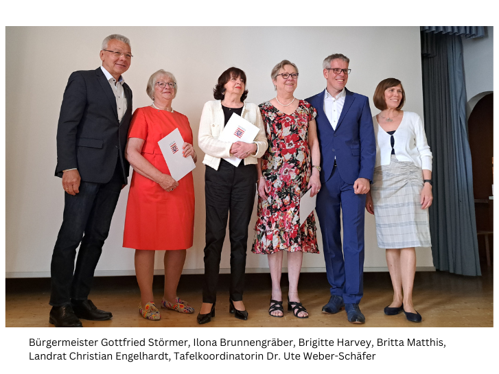 Bürgermeister Störmer steht links neben den drei Tafelmitarbeiterinnen, die den Landesehrenbrief halten. rechts daneben stehen Landrat Engelhardt und Tafelkoordinatorin Weber-Schäfer auf der Bühne in der Notkirche Lampertheim.