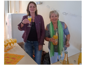 Marion Persson und Regina Fischer, Mitarbeiterinnen der Diakonie Bergstraße, schenken an einem Tisch Sekt und Orangensaft aus,