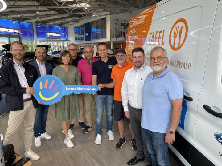 9 Personen stehen in einer Halle neben einem neuen E-Transporter mit der Aufschrift Tafel . Die Personen in der Mitte halten 4 Personen einen großen Schlüssel aus Pappe in die Kamera. Darauf steht Fernsehlotterie. Das Bild zeigt die Übergabe die Übergabe des E-Transporters für die Tafel Rimbach. Die Tafel Rimbach hatte in der Fernsehlotterie 50000 Euro gewonnen und konnte von diesem Geld einen E-Transporter erwerben.