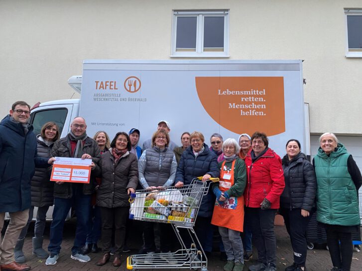 Vor dem Gebäude der Tafel-Ausgabestelle in Rimbach wurde das Foto vor dem Kühlauto der Tafel aufgenommen. Davor stehen Dekan Kreh mit dem Spendenscheck, Leitung der Diakonie, Koordinatorin der Tafel und ehrenamtliche Mitarbeitende der Tafel Rimbach.