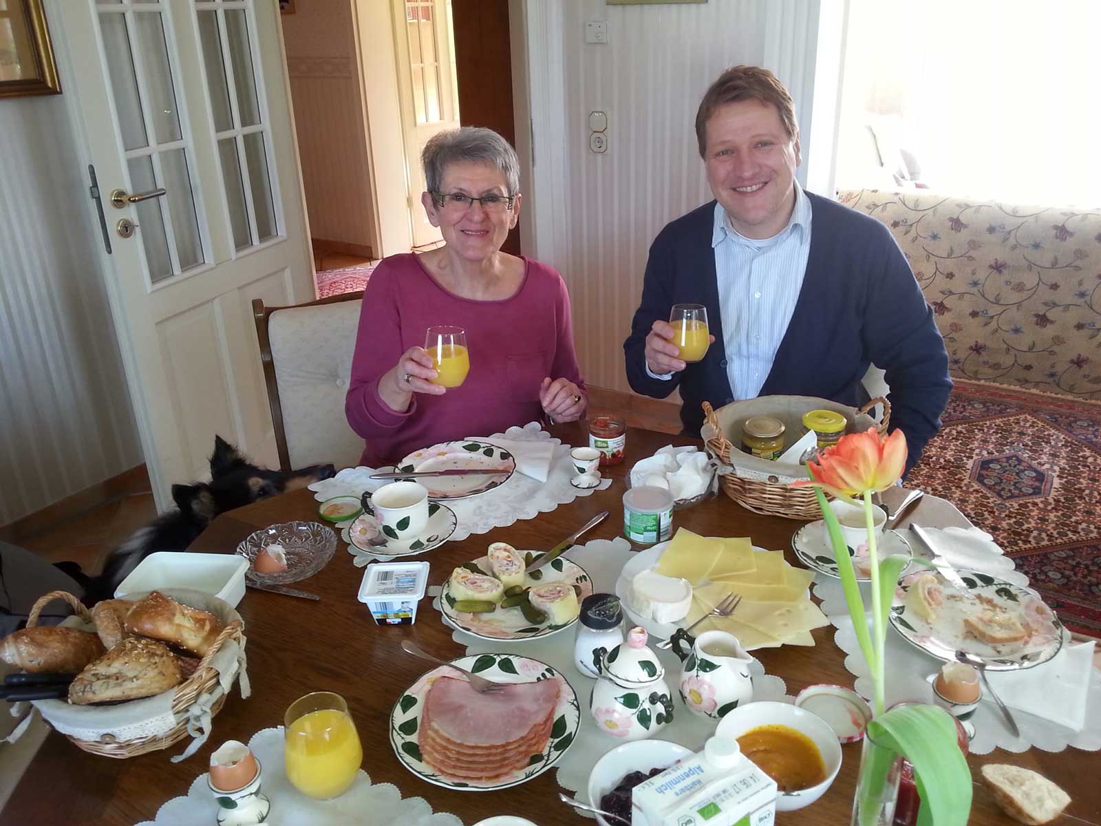 Zwei Personen sitzen an einem schön gedeckten Frühstückstisch.