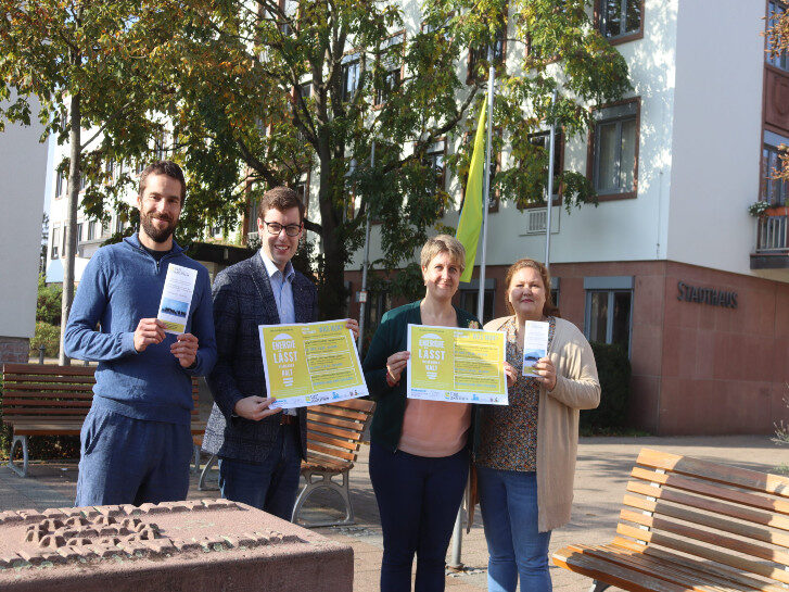 Vor dem Stadthaus stehen Andreas Dexler, Marius Schmidt, Kerstin Biehal und Jennifer Zintel-Andres. In der Hand halten sie die Plakate derVeranstaltungsreihe zu Energie und einen Flyer.