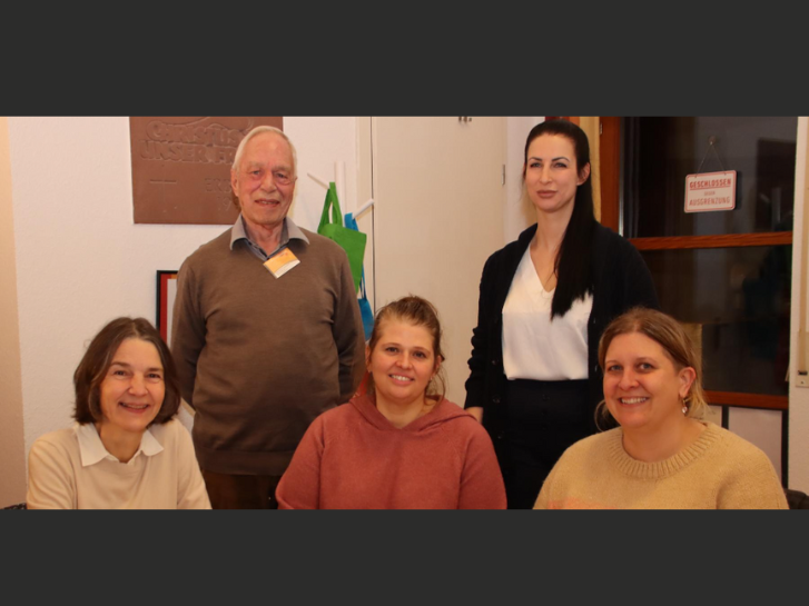 Auf dem Bild sitzen in vorderer Reihe drei Frauen, dahinter steht ein Mann und eine weitere Frau