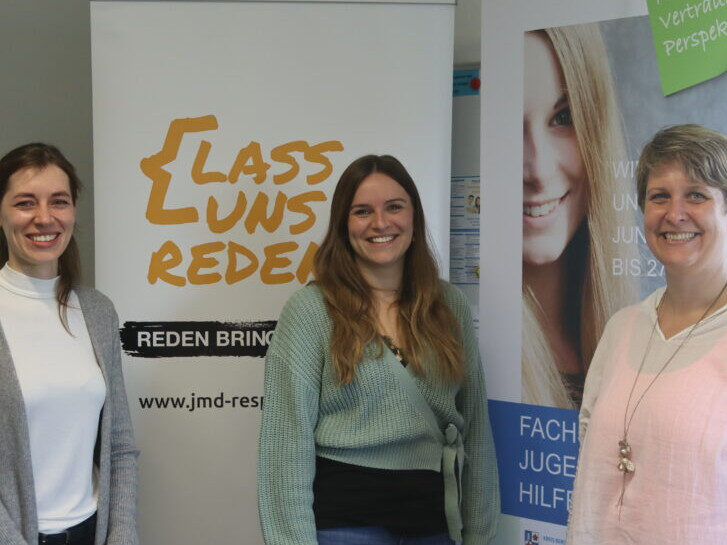 Im Hintergrund stehen zwei Rollups. Im Vordergrund von links nach rechts Carolin Schlecher, Janine Klingler, Kerstin Biehal