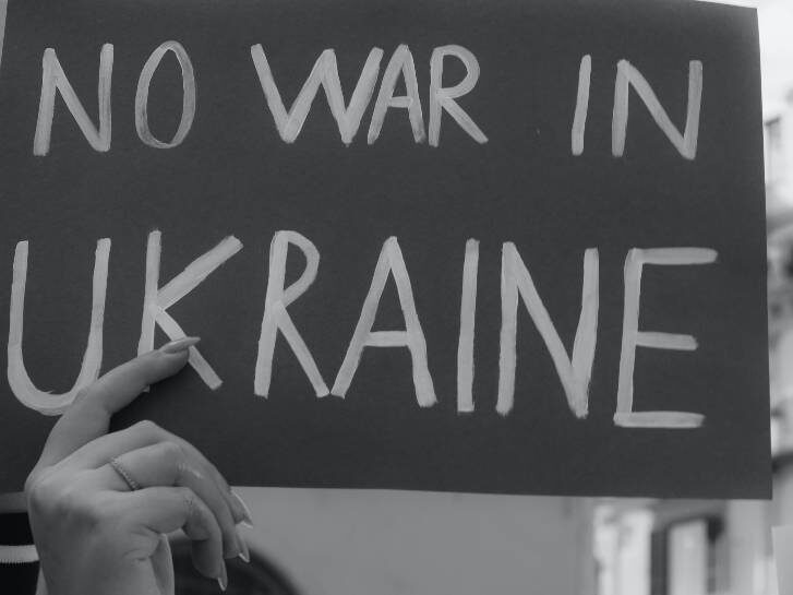 Foto zeigt Frauenhand, die ein selbstgemaltes Bild hochhält mit der Aufschrift "NO WAR IN UKRAINE"