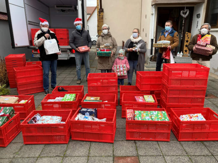 Bei der Geschenkeübergabe (Personen von links nach rechts): Peter Zimoch (Fahrer der Tafel Rimbach), Wolfgang Hoppe (Fahrer der Tafel Rimbach), Katrin Pietschmann mit Tochter Johanna, Sandra Olf, Volker Götz, Pfarrer Martin Müller. Im Vodergrund rote Kisrten mit vielen Präsenten. Im Hintergrund steht der Lastwagen der Tafel Rimbach.